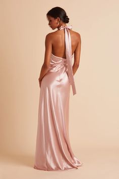 the back of a woman wearing a pink dress with a large bow at the neck