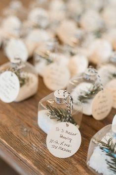 small christmas ornaments are sitting on a wooden table with tags attached to the top of each ornament