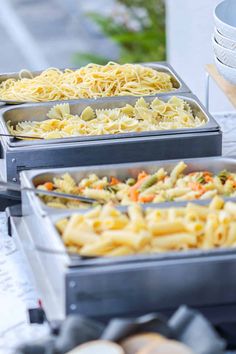 three pans filled with different types of food on top of a white tablecloth