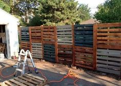 a fence made out of pallets and wooden slats is being worked on by a man