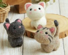 three small stuffed animals sitting next to each other on a wooden table near a potted plant