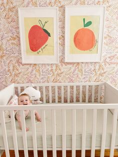 a baby laying in a crib next to two paintings