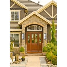 the front entrance to a house with stone and wood trimmings on the windows