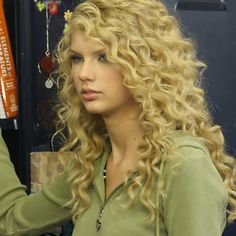 a woman with long curly blonde hair and green shirt