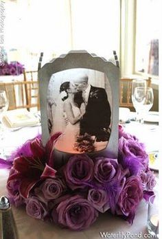 a table topped with purple flowers and an old fashioned photo frame on top of it