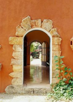 an arched doorway leading into a courtyard with plants growing in the foreground and stone work on the walls