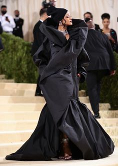 a woman in a black gown and head scarf walks down the stairs at an event