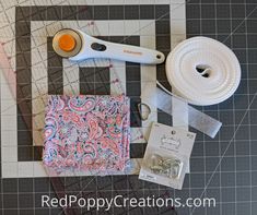 sewing supplies laid out on top of a piece of fabric and scissors, thread, tape, and other items