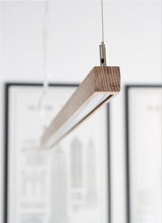 a wooden object hanging from the ceiling in front of two framed pictures and one light fixture