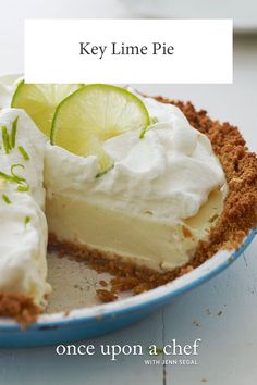 a key lime pie on a plate with whipped cream and limes in the background