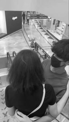 two people sitting on an escalator wearing masks