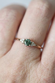 a woman's hand with a green and white diamond ring on top of her finger