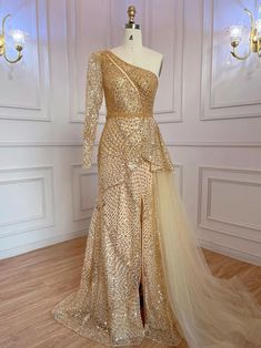 a dress on display in a room with white walls and wooden floors, gold sequins