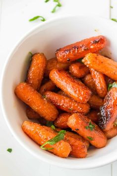 a white bowl filled with cooked carrots on top of a table