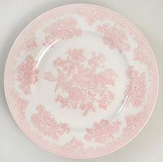 a pink and white plate with floral designs on the rim, against a white background