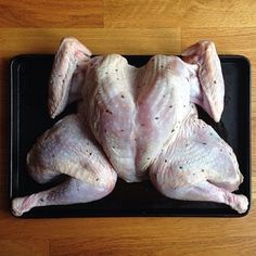 a raw chicken is laying on a black platter and ready to be cooked in the oven