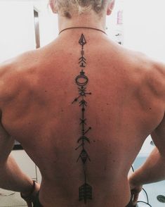 the back of a man with an arrow tattoo on his upper and lower back tattoos