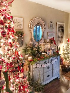 a living room decorated for christmas with red and white ornaments on the tree, wreaths and other holiday decorations