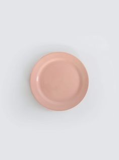 an empty pink plate sitting on top of a white surface with no one around it