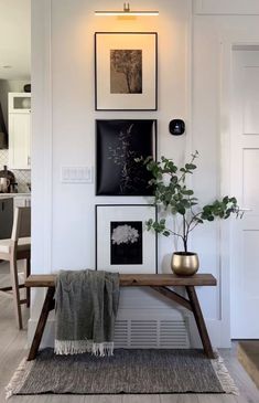 a wooden bench sitting in the middle of a living room next to a wall with pictures on it