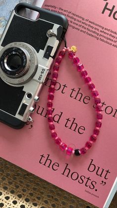 an old camera and pink beaded necklace on top of a book with the words hot