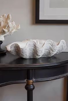 a black table topped with a white vase filled with water and a seashell on top of it