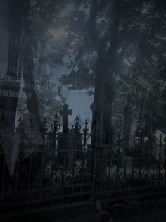 an iron fence and gate in front of a cemetery with tombstones on it at night