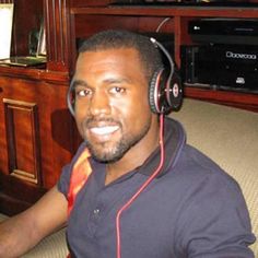 a man with headphones on sitting in front of a television set and looking at the camera