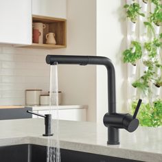 a kitchen faucet with water running from it's spout, next to a sink