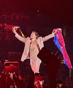 the man is performing on stage with his hands in the air while holding an umbrella