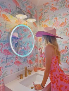 a woman in a pink hat is looking at her reflection in the mirror while brushing her teeth