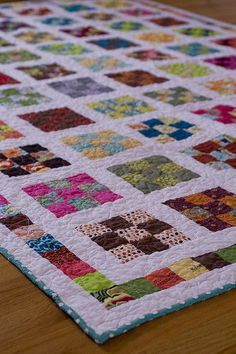 a close up of a quilt on a wooden table with a wood floor in the background