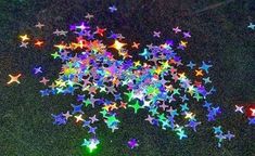 many multicolored stars are scattered on the ground in this photo, and one is lit up