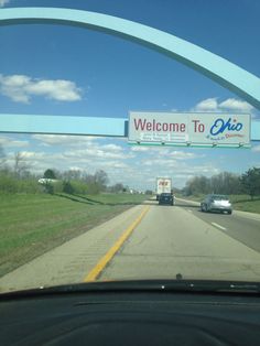 a welcome to ohio sign hanging from the side of a car door over a highway