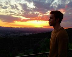 a man standing on top of a balcony next to a sunset