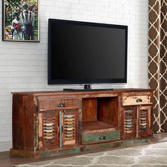 a flat screen tv sitting on top of a wooden entertainment center next to a window