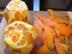 an orange cut in half sitting on top of a wooden cutting board next to other sliced up fruit