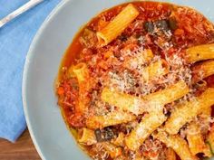 a bowl filled with pasta and sauce on top of a blue napkin next to a fork