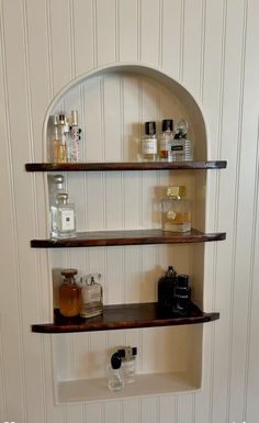 three shelves with bottles on them in a bathroom