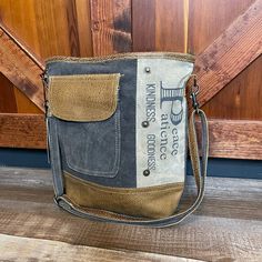 Up-Cycled From Canvas, Denim, And Leather Fully Lined Interior With 2 Slip Pockets And One Zip Pocket Back Exterior Has A Zip Pocket Front Exterior Has A Slip Pocket Under Leather Flap Dimensions: 12" H X 13.5" W; Shoulder, 23.5" Adjustable This Bag Is Made Of Up-Cycled Military Tents. Slight Variations, Including Stitch Marks And Minor Staining On The Canvas Or Leather, Are Possible. Each Bag Is Handcrafted With The Spirit Of Vintage Gray Shoulder Bucket Bag For Everyday Use, Gray Canvas Shoulder Bag With Leather Handles, Gray Shoulder Bucket Bag, Daily Use Upcycled Satchel Shoulder Bag, Upcycled Canvas Satchel Shoulder Bag, Upcycled Canvas Shoulder Bag For Daily Use, Upcycled Canvas Bag For Everyday Use, Upcycled Canvas Crossbody Bag, Everyday Upcycled Crossbody Bag