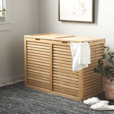 a wooden laundry hamper next to a potted plant