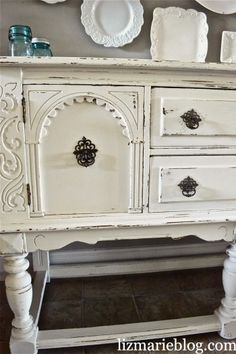 an old white dresser with ornate carvings and knobs on it's doors is shown