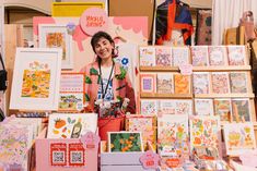 a woman standing in front of a table full of cards and greeting cards for sale