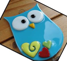 a blue plate with an owl painted on it's face and two hearts attached to the side