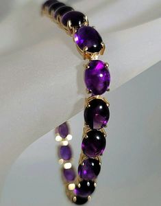 Beautiful bracelet! Marked 14K yellow gold amethyst cabochon cut gemstone bracelet. The 14K yellow gold bracelet is set with nineteen oval shaped cabochon cut amethyst gemstones. Each amethyst measures approximately 8.00 mm x 6.50 mm for an approximate total amethyst weight of 23.75 carats. The amethyst set in the bracelet are well matched in a fine quality and color. The amethyst display a vivid purple color with red flash. The 14K yellow gold amethyst bracelet has a solid and secure 14K yellow gold clasp with a safety catch. The amethyst bracelet measures approximately 7 1/4 inches long. The 14K yellow gold amethyst bracelet weighs 15.00 grams.   The amethyst bracelet comes in a quality bracelet box.  You can feel secure knowing that the 14K yellow gold amethyst bracelet was professional Formal Amethyst Oval Cabochon Jewelry, Formal Amethyst Jewelry, Oval Cabochon, Formal Purple Oval Cabochon Jewelry, Oval Amethyst Jewelry Collectible, Elegant Cabochon Amethyst Gemstones, Elegant Amethyst Cabochon Gemstones, Luxury Purple Cabochon Jewelry, Formal Purple Cabochon Gemstones, Classic Oval Cabochon Amethyst Jewelry