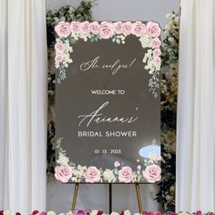 a welcome sign with pink roses and greenery in the background for a bridal shower