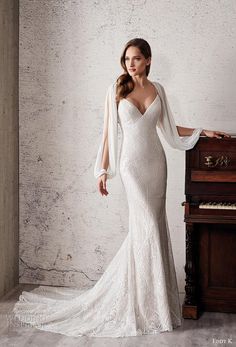 a woman in a white dress standing next to a piano and wearing a shawl