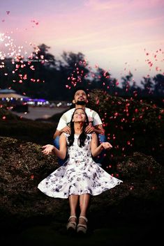 a man sitting on top of a woman's lap as fireworks fly in the sky