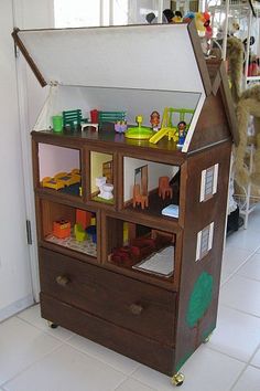 a toy house made out of wood with lots of toys in the room around it