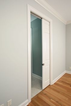 an empty room with white doors and hard wood flooring on either side of the door